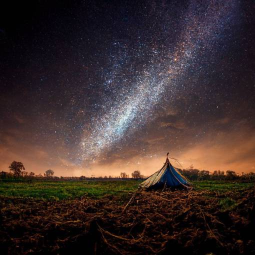small tent, big field. Night sky. Milky way. Long exposure photograph.