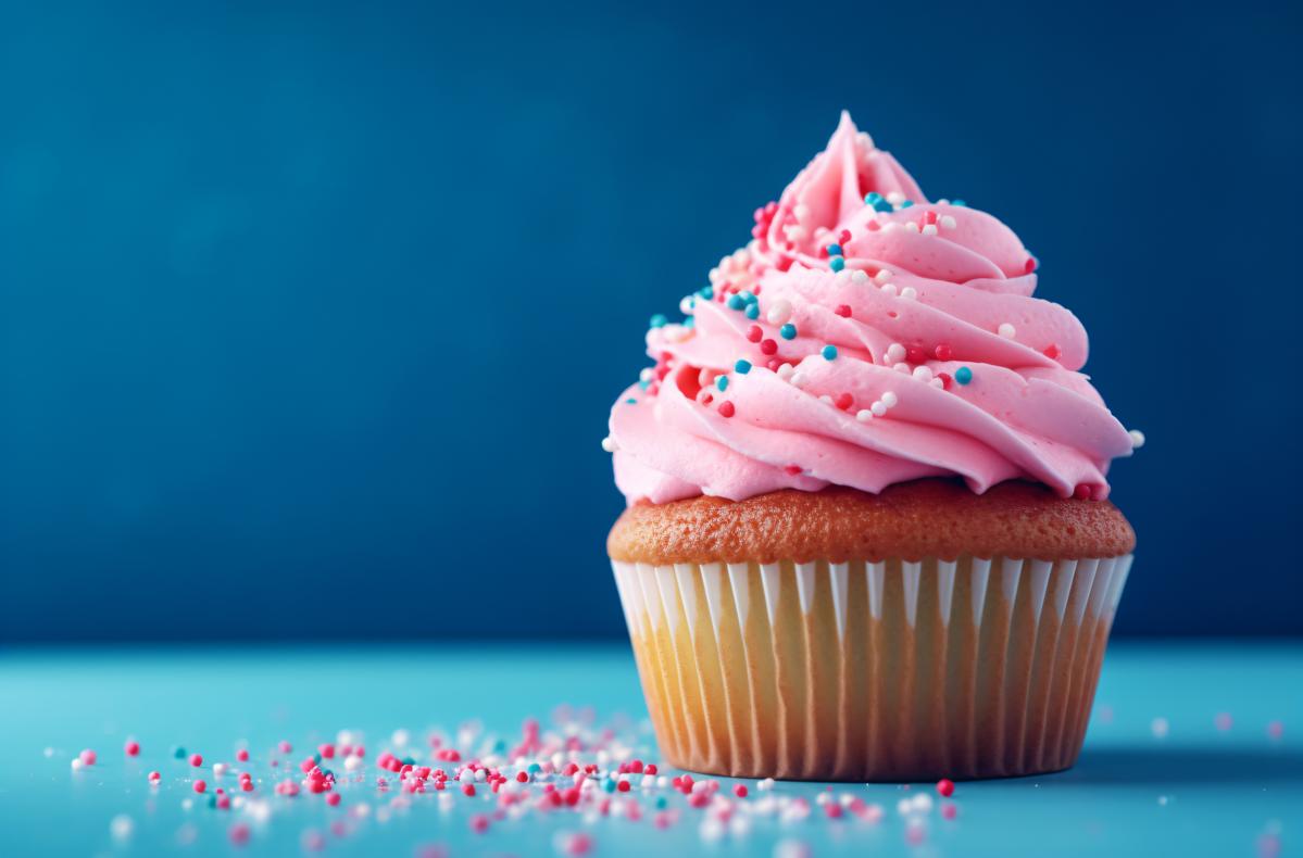 a pink cupcake with sprinkles on a blue background picture